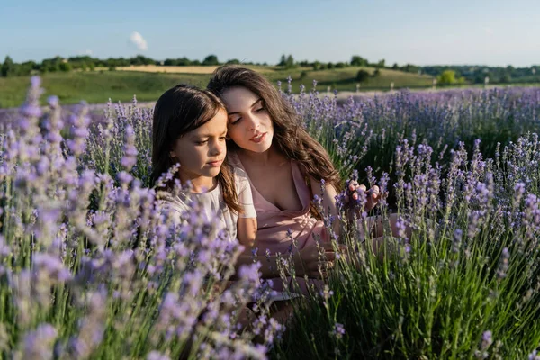 Brunette woman and girl sitting in lavender field on summer day — Stockfoto
