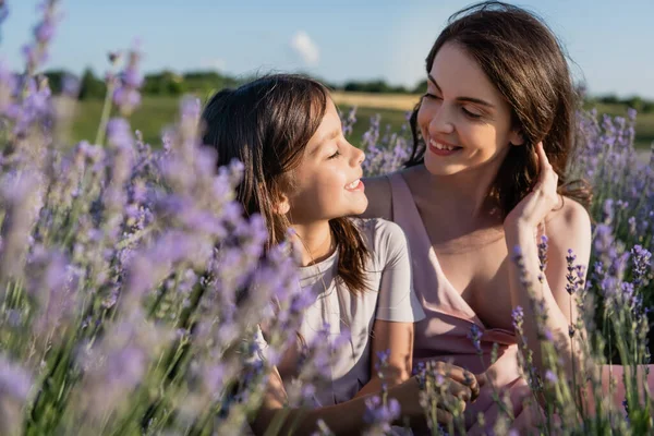 Happy mom and daughter smiling at each other in blurred lavender field - foto de stock