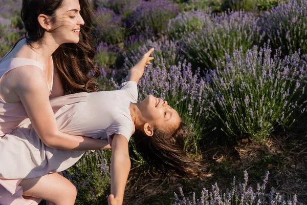 Cheerful child having fun with mother in meadow with blooming lavender — Fotografia de Stock