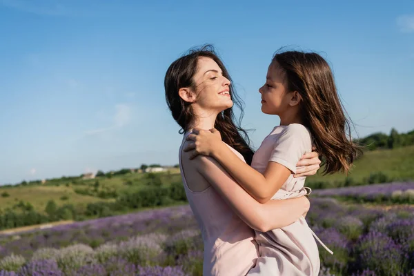 Side view of brunette mom and daughter with long hair hugging in field — Foto stock
