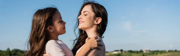 Side view of happy brunette mother and daughter looking at each other outdoors, banner — Fotografia de Stock