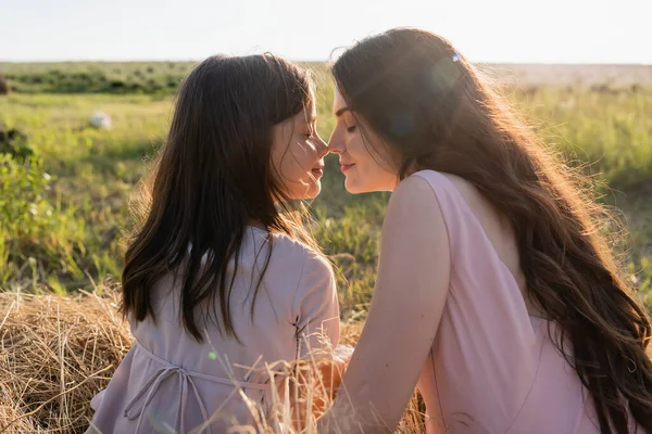 Brunette mother and daughter with closed eyes smiling face to face in meadow — Fotografia de Stock