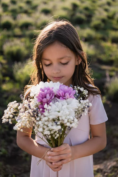 Girl with long hair holding bouquet of flowers in meadow — Photo de stock