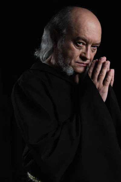 Serious monk looking at camera while praying isolated on black — Stock Photo