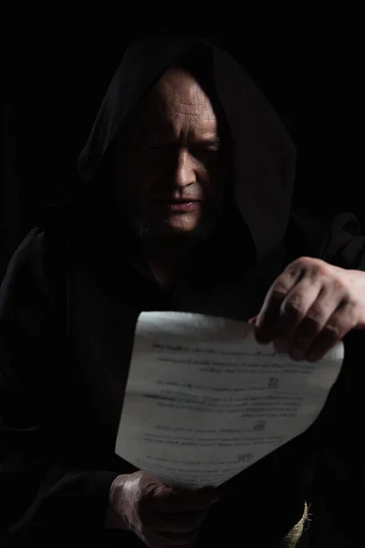 Senior medieval monk reading ancient manuscript isolated on black — Stock Photo