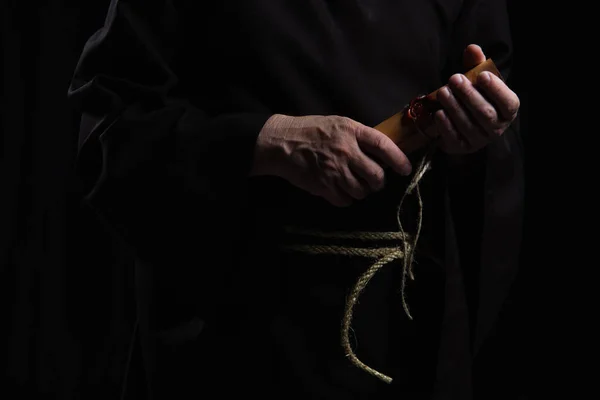 Partial view of abbot holding rolled manuscript with wax seal isolated on black — Stock Photo