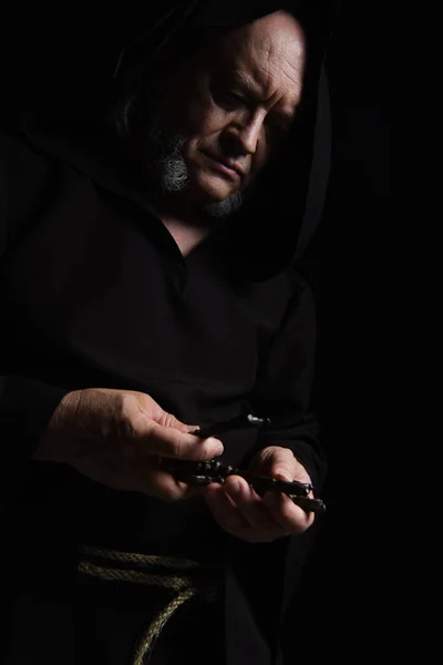 Medieval monk in hooded cassock holding keys isolated on black — Stock Photo