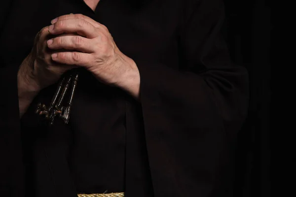 Cropped view of senior priest with keys isolated on black — Stock Photo