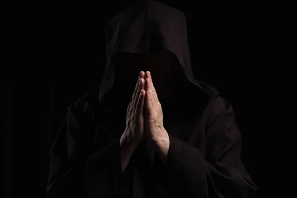 Front view of mysterious anonymous monk with praying hands isolated on black — Stock Photo