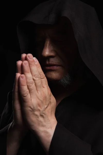 Monge medieval com os olhos fechados e mãos de oração isolado em preto — Fotografia de Stock