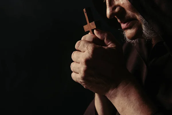 Cropped view of medieval monk praying with crucifix isolated on black — Stock Photo