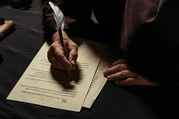 Vue partielle du moine en soutane noire écriture chronique sur parchemin — Photo de stock