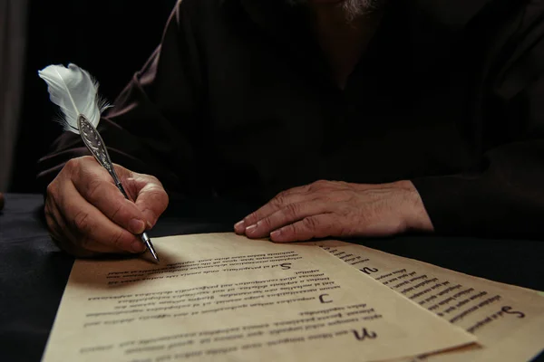 Vista recortada del manuscrito de escritura monje en pergamino aislado en negro - foto de stock