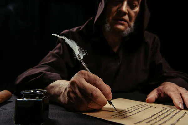 Blurred medieval monk writing manuscript with feather pen isolated on black — Stock Photo