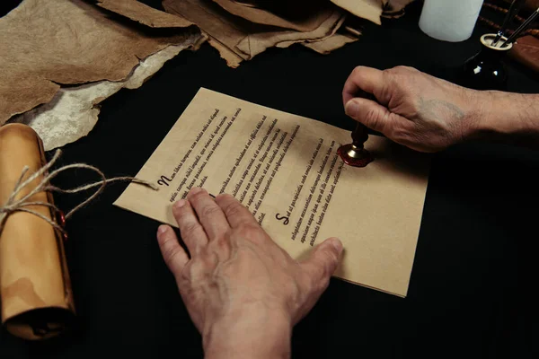 Partial view of priest stamping medieval manuscript with wax seal — Stock Photo