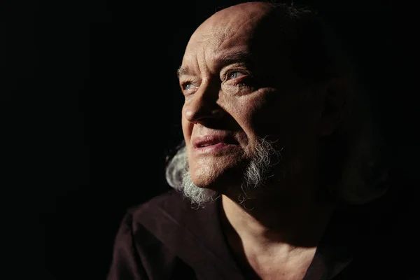 Portrait de moine aîné avec barbe regardant loin isolé sur noir — Photo de stock