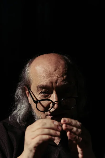 Pensive medieval philosopher in eyeglasses looking at camera isolated on black — Stock Photo