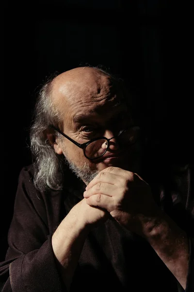 Позитивный религиозный философ в очках, смотрящий на камеру, изолированную от черного — стоковое фото