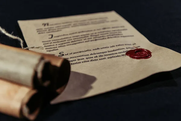 Manuscript stamped with wax seal near rolled parchments on black background — Stock Photo