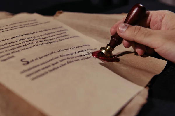 Partial view of senior monk approving chronicle with wax seal on black surface — Stock Photo