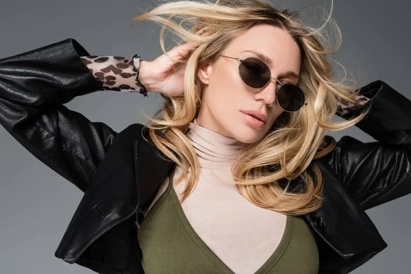 Blonde model in leather jacket and stylish sunglasses posing isolated on grey — Fotografia de Stock