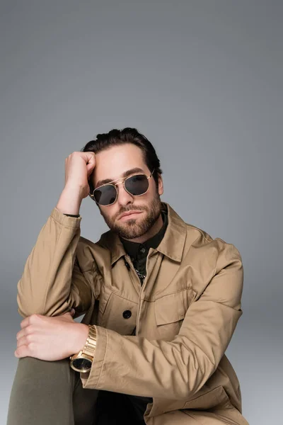 Bearded man in stylish outfit and sunglasses looking at camera isolated on grey — Stockfoto