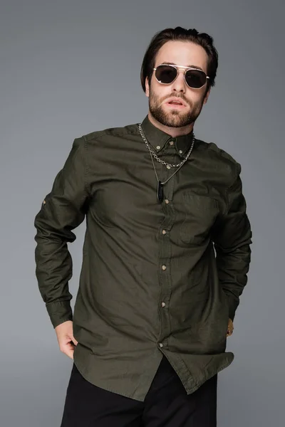 Bearded man in stylish green shirt and sunglasses looking at camera isolated on grey — Stock Photo