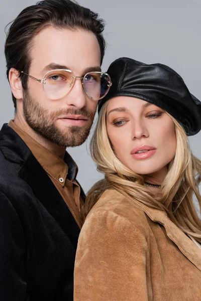 Portrait of blonde woman in stylish beret near bearded man in sunglasses isolated on grey — Fotografia de Stock