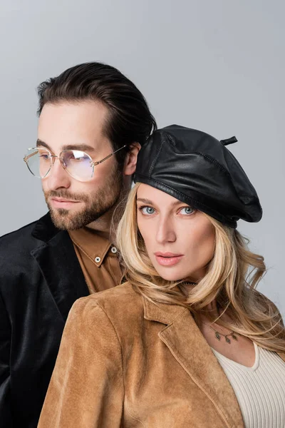 Blonde woman in black leather beret near bearded man in sunglasses isolated on grey — Stock Photo