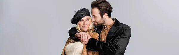 Happy man hugging happy blonde woman in stylish beret isolated on grey, banner - foto de stock
