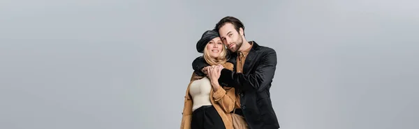 Cheerful man hugging happy woman in stylish beret isolated on grey, banner — Stockfoto