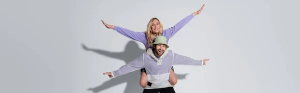 Cheerful woman and happy man in panama hat posing with outstretched hands on grey, banner — Photo de stock