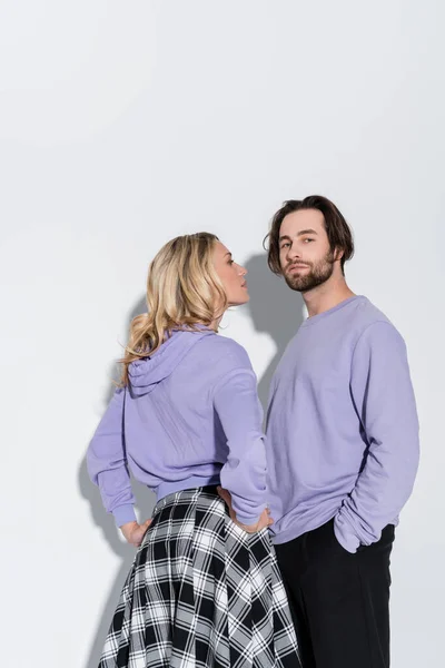Blonde woman in purple sweatshirt looking at stylish bearded man on grey — Photo de stock