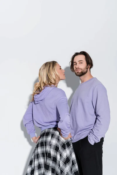 Blonde woman in purple sweatshirt looking at stylish bearded man on grey — Fotografia de Stock