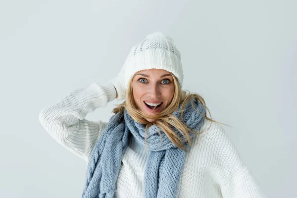 Portrait of amazed woman in winter hat and knitted scarf looking at camera isolated on grey — Fotografia de Stock