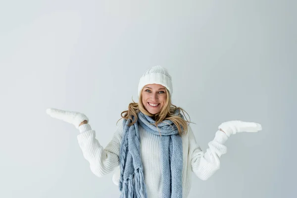 Портрет веселой женщины в зимней шляпе и вязаном шарфе, смотрящей на камеру, изолированную на сером — стоковое фото