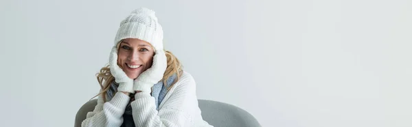Happy blonde woman in winter outfit and soft white gloves isolated on grey, banner - foto de stock