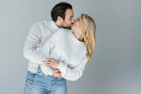 Bearded man and blonde woman in knitted sweaters kissing isolated on grey — Photo de stock