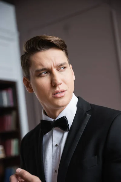 Портрет элегантного мужчины в формальной одежде, смотрящего в сторону дома — стоковое фото