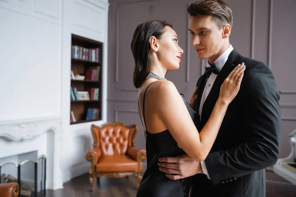 Young woman in dress hugging boyfriend in formal wear at home — Stock Photo