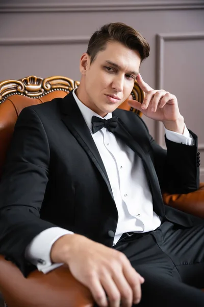 Elegant man in suit sitting on leather armchair at home — Stock Photo