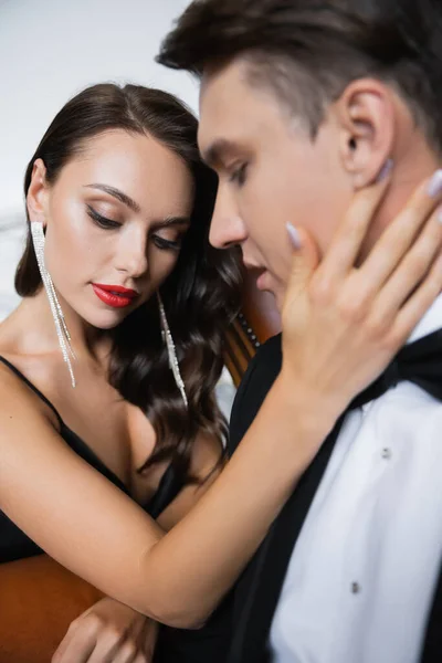 Young woman with red lips touching blurred boyfriend in suit at home — Stock Photo