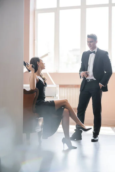 Elegant woman holding gun near boyfriend with whiskey — Stock Photo