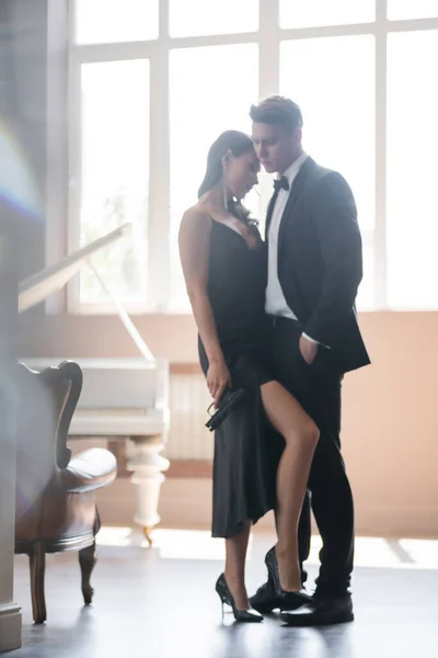 Sensual woman holding gun near boyfriend in suit at home — Stock Photo