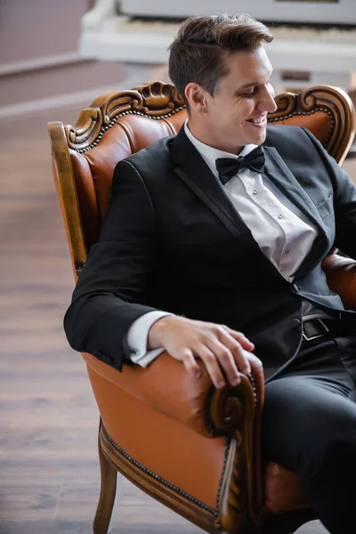 Cheerful man in suit sitting on armchair at home — Stock Photo