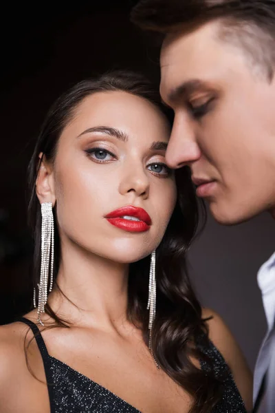 Elegant woman with red lips looking at camera near blurred boyfriend — Stock Photo