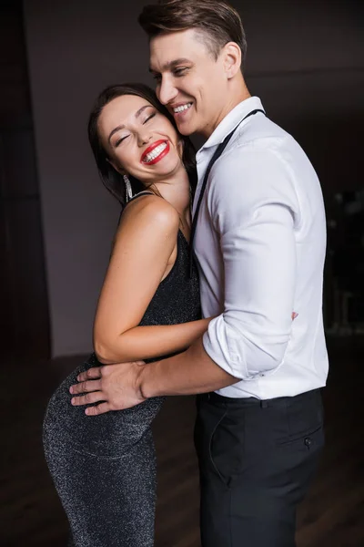 Cheerful woman in dress hugging boyfriend at home — Stock Photo