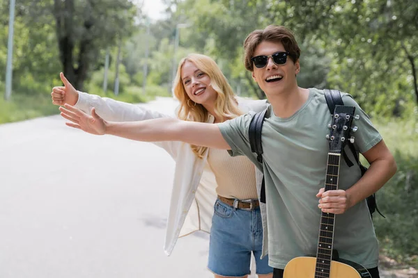 Young and happy hitchhikers stopping car on countryside road — Fotografia de Stock