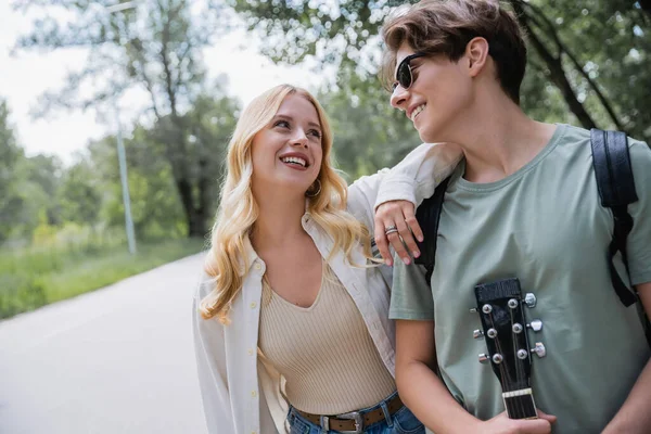 Man in sunglasses and blonde woman smiling at each other in countryside — Stockfoto