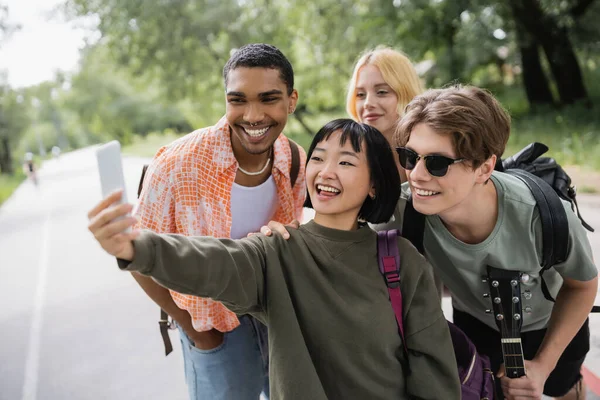 Cheerful asian woman taking selfie with multiethnic friends outdoors — Photo de stock